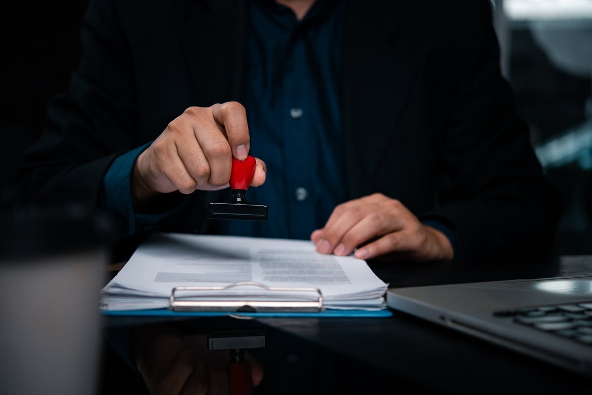 Business holding rubber stamp document approval verification. Corporate executive legal papers with official stamp document authentication. Notary service provider certify important business contract